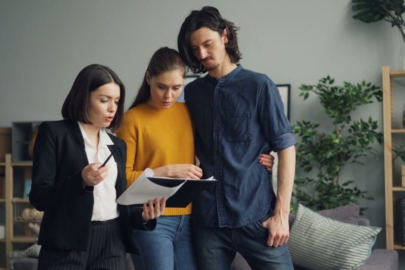 A couple reviewing documents with a real estate agent indoor 1781629493